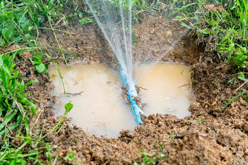 Water pipe break sprinkler irrigation system, leaking from hole in a hose connection joint of plastic pipes